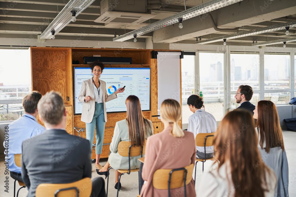 Mid adult businesswoman explaining business strategy to colleagues in training class